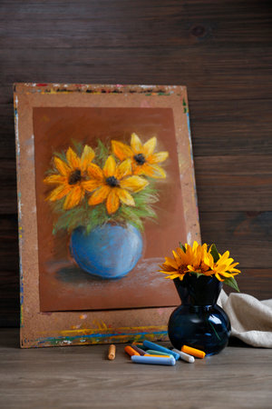 Yellow flowers, beautiful drawing and set of colorful pastels on wooden tableの写真素材