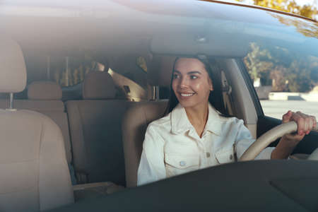Beautiful young driver sitting in modern car, view through windshield