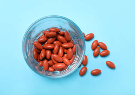 Glass with pills on turquoise background, flat lay. Anemia treatmentの写真素材