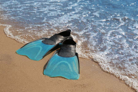Pair of turquoise flippers on sand near sea. Space for textの写真素材