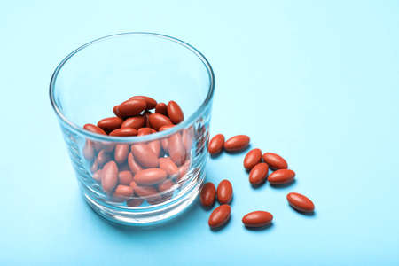 Glass with pills on turquoise background, closeup. Anemia treatmentの写真素材