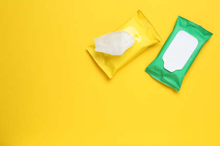 Wet wipes flow packs on yellow background, flat lay. Space for textの写真素材