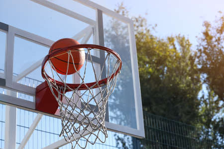Basketball ball and hoop with net outdoors on sunny dayの写真素材