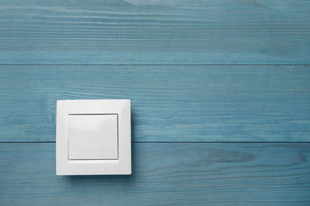 White light switch on turquoise wooden background. Space for textの写真素材