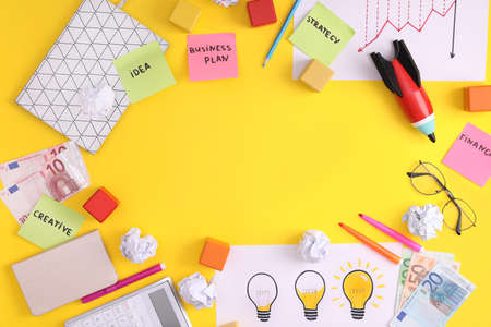 Frame of stationery, money and toy rocket on yellow background, flat lay with space for text. Startup conceptの写真素材