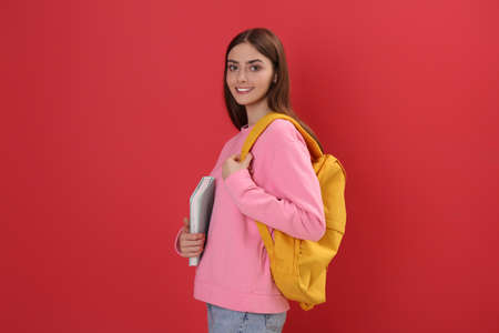 Teenage student with backpack and book on red backgroundの写真素材