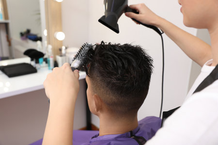 Professional hairdresser drying client's hair in salon, closeupの写真素材