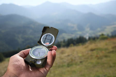 Man using compass during journey in mountains, closeup