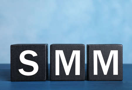 Cubes with abbreviation SMM (Social media marketing) on blue tableの写真素材