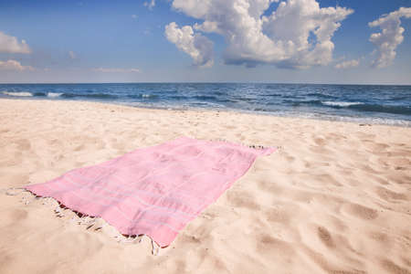 Pink striped beach towel on sandy seashoreの写真素材
