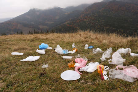 Plastic garbage scattered on grass in natureの写真素材