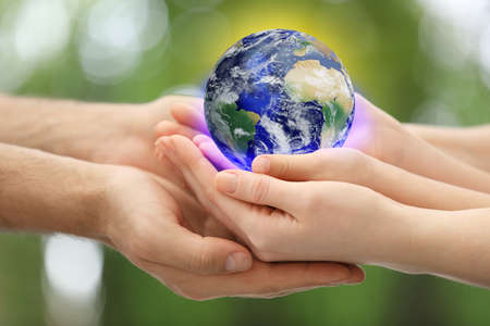 World in our hands. Closeup view of parents and kid holding digital model of Earth on blurred green...
