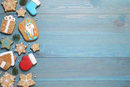 Tasty gingerbread cookies and fir branches on light blue wooden table, flat lay with space for text. St. Nicholas Day celebrationの写真素材
