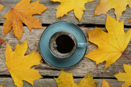 Cup of hot coffee and autumn leaves on wooden table, flat layの写真素材
