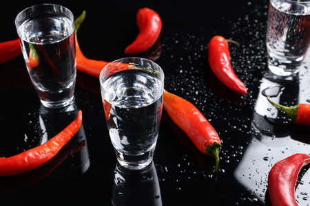 Red hot chili peppers and vodka on black tableの写真素材