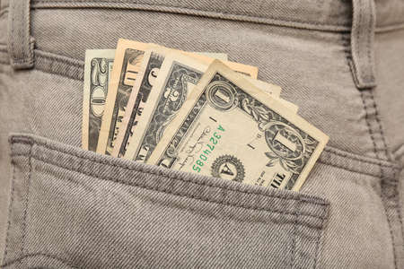 Dollar banknotes in pocket of gray jeans, closeup. Spending money