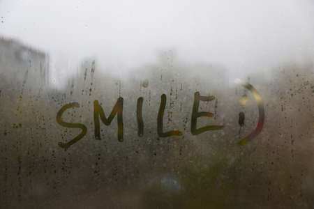 Word SMILE written on foggy window. Rainy weatherの写真素材