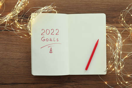 Open planner, felt tip pen and Christmas lights on wooden table, flat lay. Planning for 2022 New Yearの写真素材