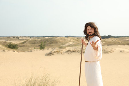 Jesus Christ walking with stick in desert. Space for textの写真素材