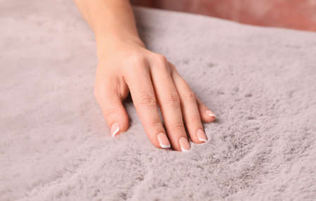 Woman touching soft light gray fabric indoors, closeup