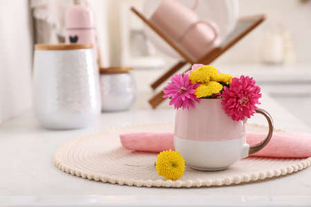 Beautiful bright flowers in cup on table indoors, space for textの写真素材