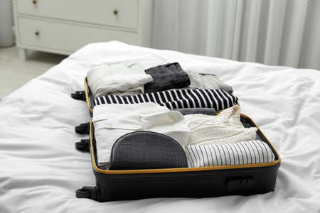 Open suitcase with clothes on bed indoorsの写真素材