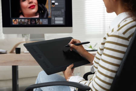 Professional retoucher working with graphic tablet at desk in office, closeup
