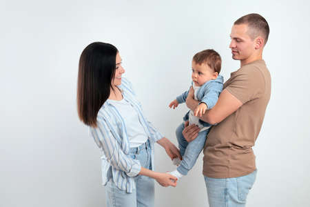 Happy parents with cute child on light background