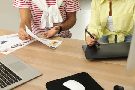 Professional retoucher with colleague working at desk in office, closeup