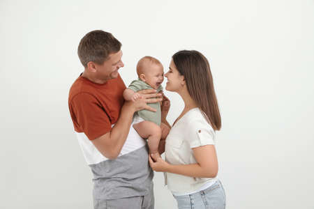 Portrait of happy family with their cute baby on white background