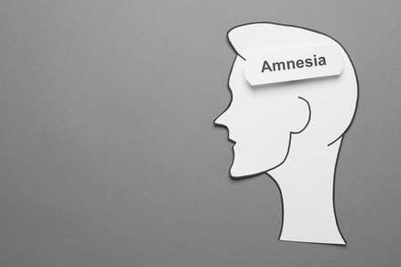 Card with word Amnesia and human head cutout on gray background, top view. Space for textの写真素材