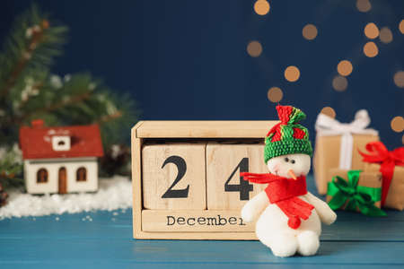 Christmas Eve - December 24. Block calendar and cute toy snowman on light blue wooden tableの写真素材