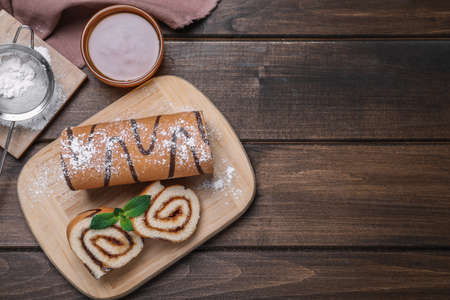 Tasty cake roll with jam on wooden table, flat lay. Space for textの写真素材