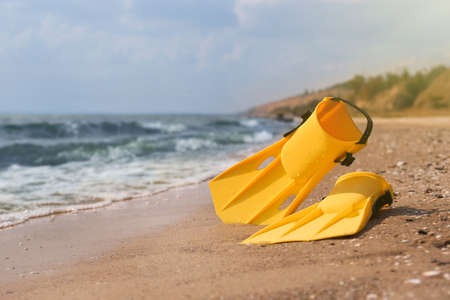 Pair of yellow flippers on sand near sea. Space for textの写真素材