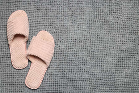 Slippers on soft gray bath mat, flat lay. Space for text