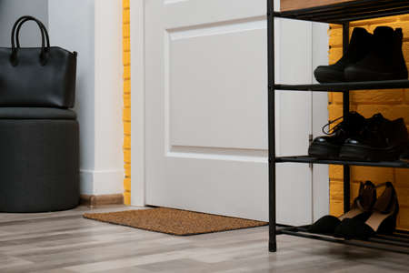 Door mat and shelving unit with shoes in hallwayの写真素材