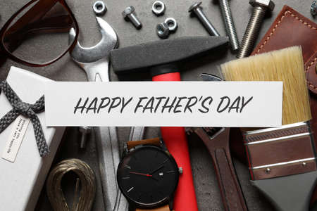 Card with phrase HAPPY FATHER'S DAY, different tools and male accessories on gray background, flat layの写真素材