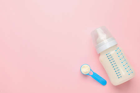 Feeding bottle with infant formula and powder on pink background, flat lay. Space for textの写真素材