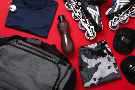 Gray sports bag and roller skating equipment on red background, flat layの写真素材