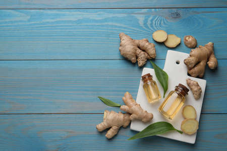 Glass bottles of essential oil and ginger root on light blue wooden table, flat lay. Space for textの写真素材