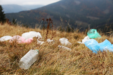 Plastic garbage scattered on grass in natureの写真素材