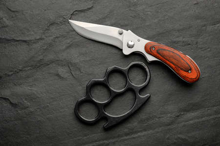 Brass knuckles and knife on black background, flat layの写真素材
