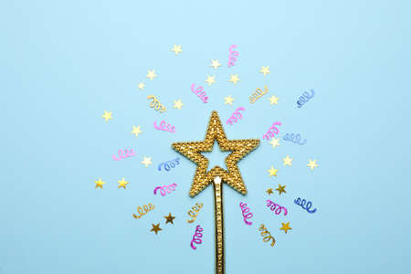 Beautiful golden magic wand and confetti on light blue background, flat layの写真素材