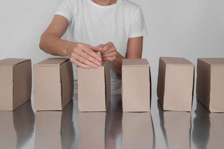 Woman folding cardboard boxes at table, closeup. Production lineの写真素材