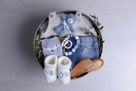 Box with baby clothes, booties and accessories on gray background, top viewの写真素材