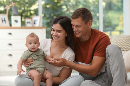 Portrait of happy family with their cute baby at home