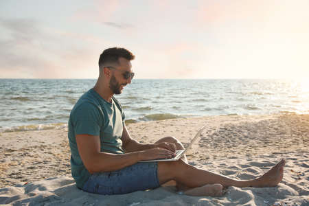Man working with modern laptop on beachの写真素材