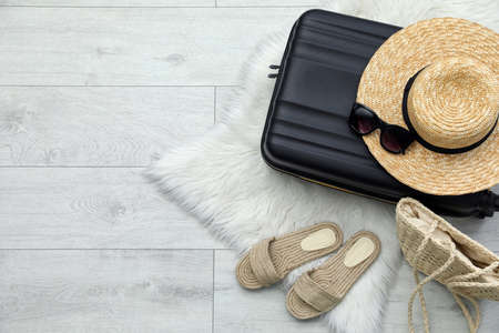 Suitcase and summer accessories on floor, flat lay. Space for textの写真素材