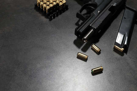 Handgun, magazine and bullets on gray table. Space for text