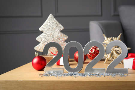 Silver number 2022 and festive decor on wooden table indoors. Happy new year